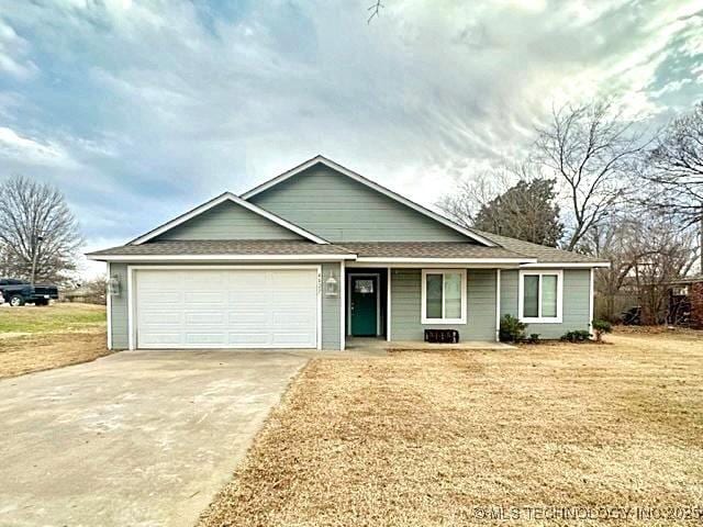 ranch-style home featuring concrete driveway, a front lawn, and an attached garage