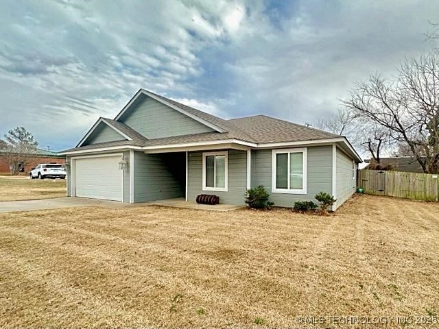 ranch-style home featuring a garage, fence, and a front lawn