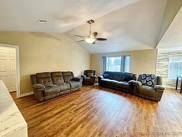 living area with a ceiling fan, vaulted ceiling, a textured ceiling, and wood finished floors