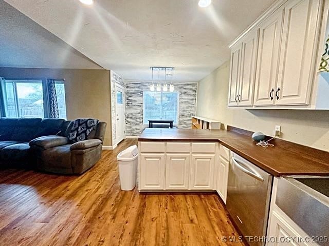 kitchen featuring open floor plan, a peninsula, stainless steel dishwasher, and light wood-type flooring