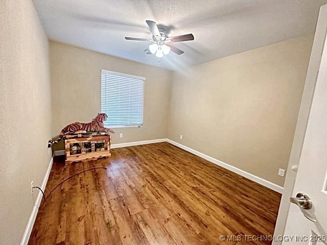 interior space with ceiling fan, a textured ceiling, baseboards, and wood finished floors