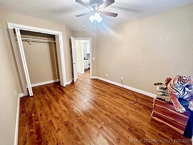 unfurnished bedroom featuring a ceiling fan, a closet, baseboards, and wood finished floors