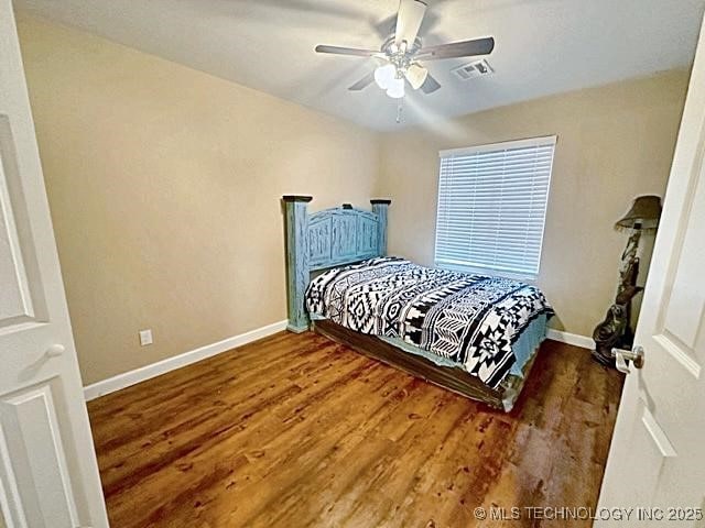 bedroom featuring a ceiling fan, baseboards, visible vents, and wood finished floors