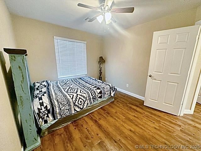 bedroom with ceiling fan, wood finished floors, and baseboards