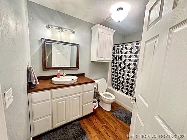 bathroom featuring toilet, shower / bath combo, wood finished floors, and vanity