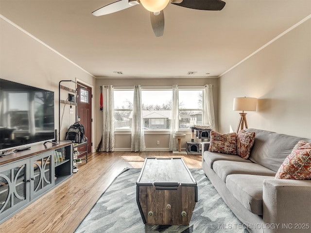 living area featuring baseboards, a ceiling fan, crown molding, and wood finished floors