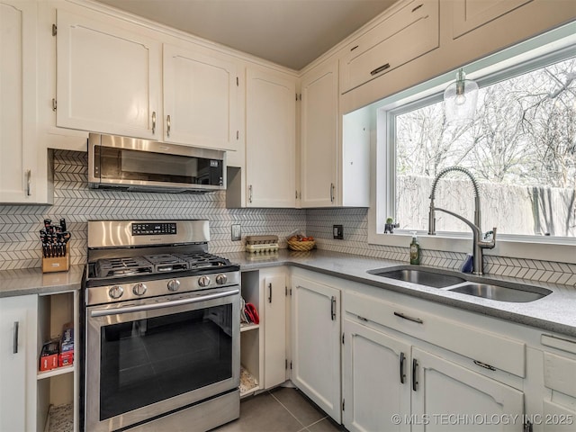 kitchen with appliances with stainless steel finishes, backsplash, a sink, and white cabinets