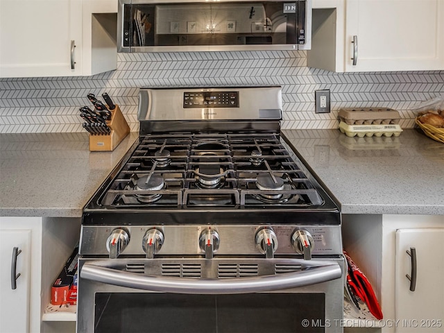 details featuring gas range, tasteful backsplash, light stone counters, and white cabinets