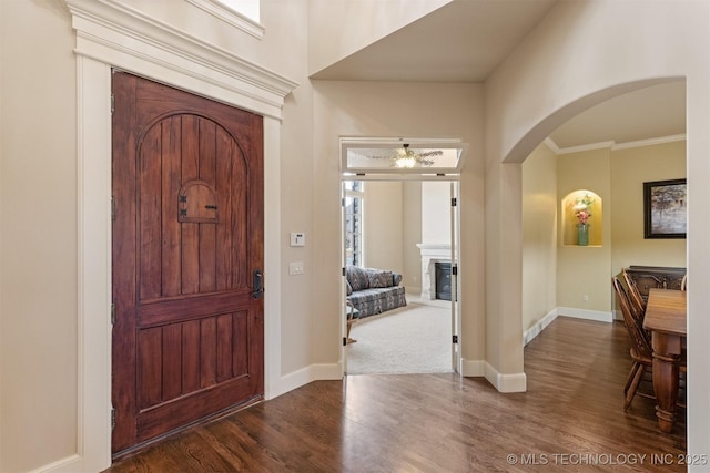 11870 S Oswego Ave, Tulsa, OK 74137 - entrance foyer featuring wood finished floors, arched walkways, baseboards, ornamental molding, and a glass covered fireplace