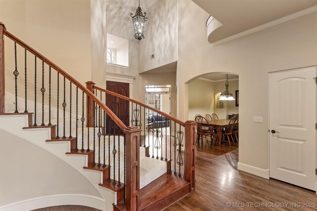 11870 S Oswego Ave, Tulsa, OK 74137 - staircase with a chandelier, ornamental molding, a towering ceiling, wood finished floors, and arched walkways