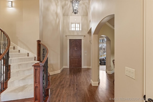 11870 S Oswego Ave, Tulsa, OK 74137 - foyer entrance with arched walkways, dark wood-type flooring, stairs, a towering ceiling, and baseboards