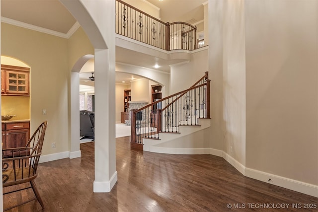 11870 S Oswego Ave, Tulsa, OK 74137 - entryway featuring dark wood finished floors, arched walkways, crown molding, stairway, and baseboards