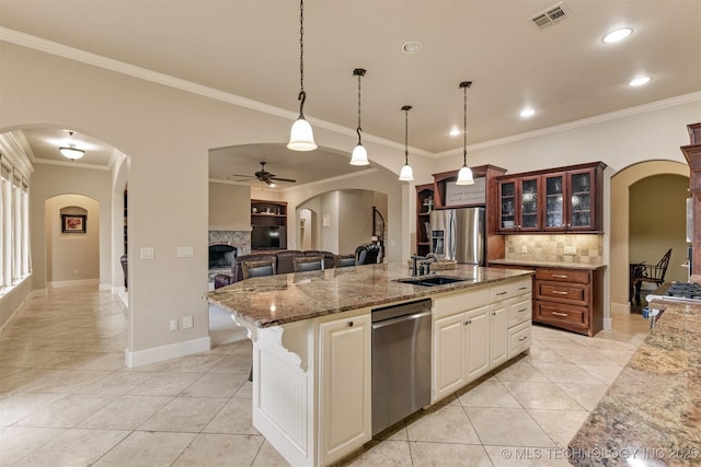 11870 S Oswego Ave, Tulsa, OK 74137 - kitchen with appliances with stainless steel finishes, light tile patterned floors, a fireplace, arched walkways, and tasteful backsplash