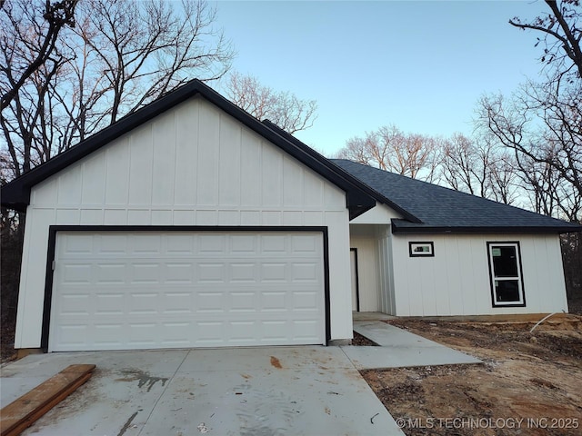 view of front of house with a garage, board and batten siding, concrete driveway, and roof with shingles