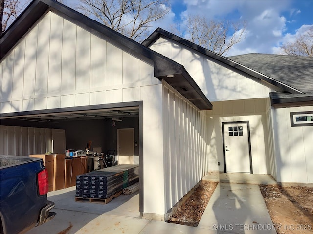 entrance to property featuring roof with shingles, board and batten siding, and an attached garage