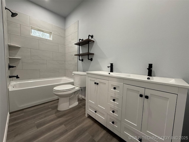 full bath with double vanity, a sink, toilet, and wood finished floors