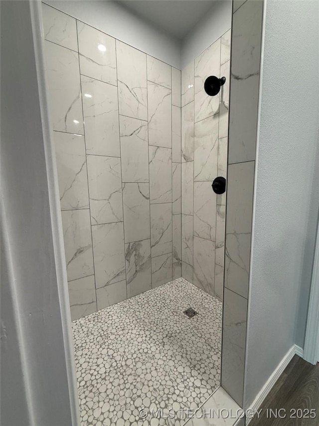 bathroom with baseboards and a tile shower