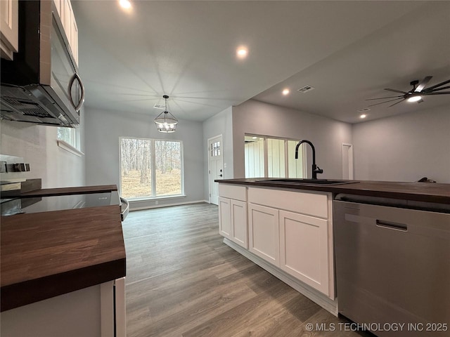 kitchen featuring light wood finished floors, stainless steel appliances, butcher block counters, white cabinetry, and a sink