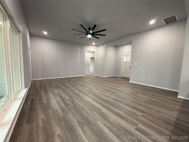 unfurnished room with dark wood-style floors, baseboards, visible vents, and a ceiling fan