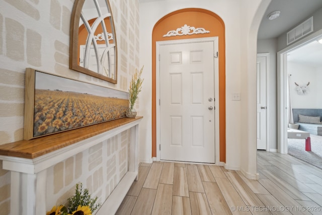 entryway with wood tiled floor, visible vents, arched walkways, and baseboards