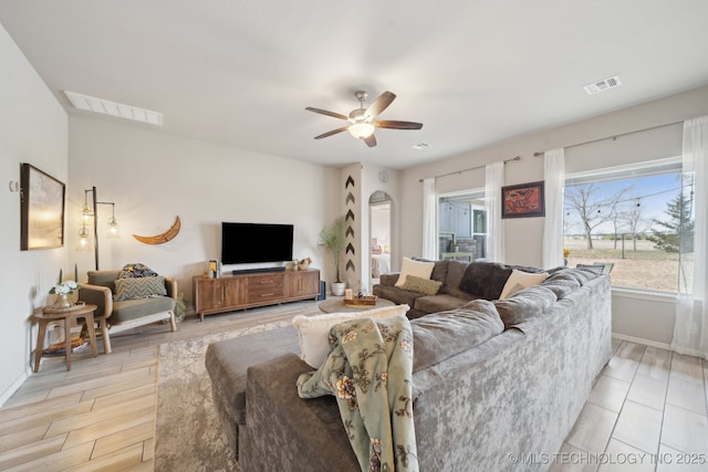 living area featuring a ceiling fan, visible vents, light wood-style flooring, and baseboards