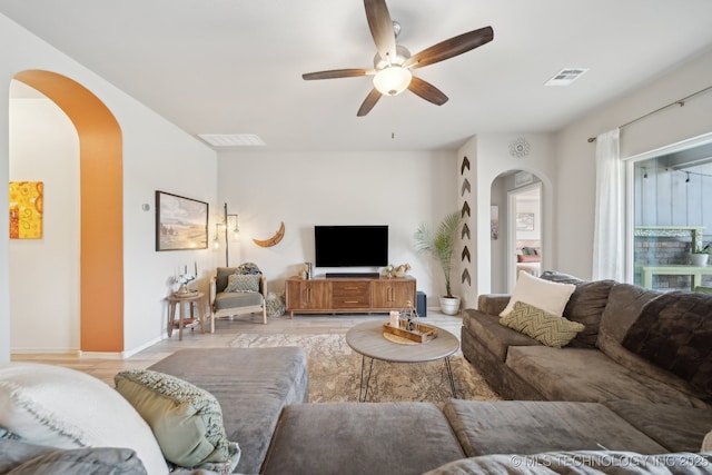 living room featuring arched walkways, baseboards, visible vents, and a ceiling fan