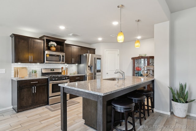 kitchen featuring appliances with stainless steel finishes, a sink, backsplash, and a breakfast bar area