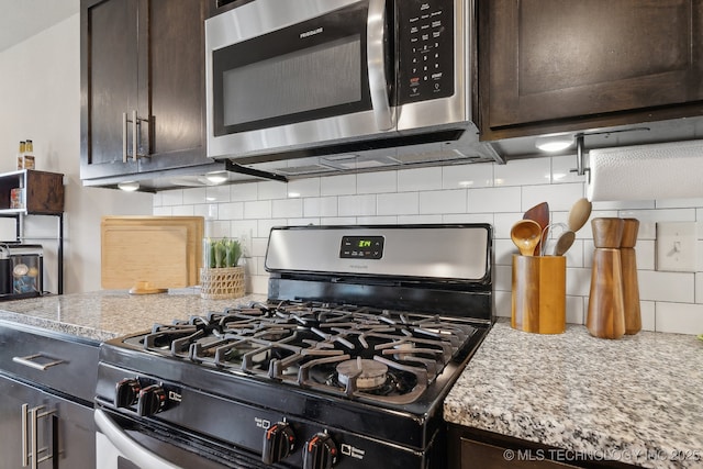 kitchen with appliances with stainless steel finishes, dark brown cabinetry, decorative backsplash, and light stone countertops