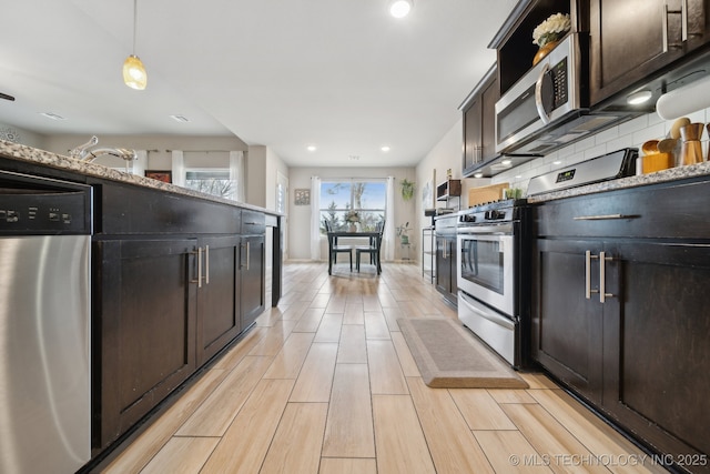 kitchen featuring decorative light fixtures, stainless steel appliances, backsplash, wood tiled floor, and dark brown cabinets