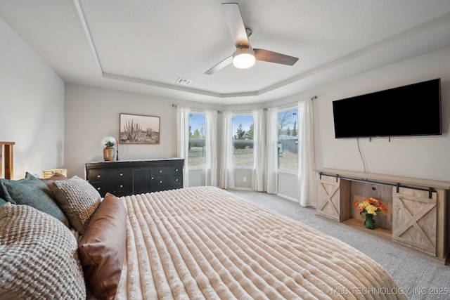 bedroom with carpet, a raised ceiling, visible vents, a ceiling fan, and baseboards