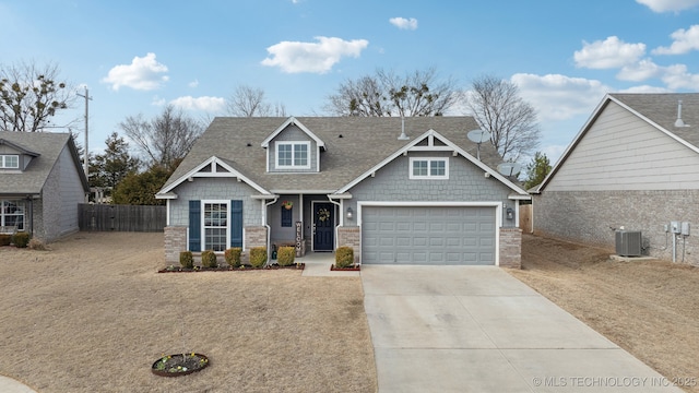 craftsman-style home featuring a shingled roof, concrete driveway, central AC, fence, and a garage