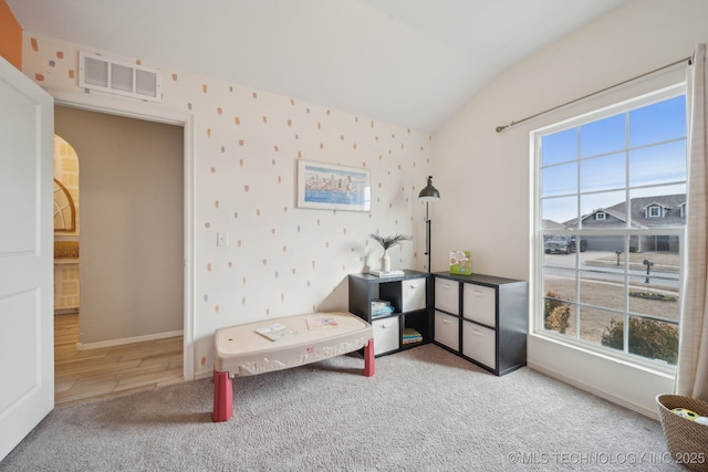 sitting room with vaulted ceiling, carpet flooring, visible vents, and baseboards