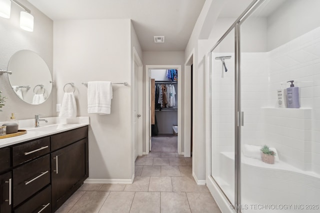 full bathroom featuring a spacious closet, a shower stall, vanity, tile patterned flooring, and baseboards