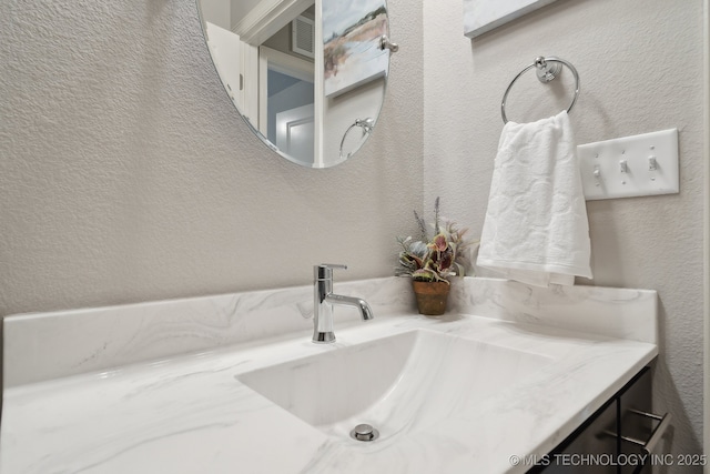 bathroom with visible vents, a textured wall, and vanity