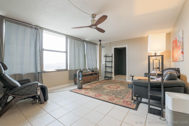 living room featuring visible vents, light tile patterned flooring, ceiling fan, a textured ceiling, and baseboards