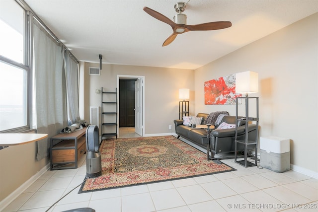 living area with light tile patterned floors, ceiling fan, visible vents, and baseboards