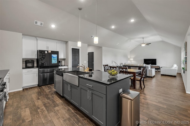 kitchen featuring wood finish floors, dark countertops, visible vents, appliances with stainless steel finishes, and a sink