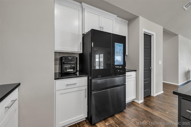 kitchen with baseboards, dark wood finished floors, visible vents, refrigerator with glass door, and white cabinetry