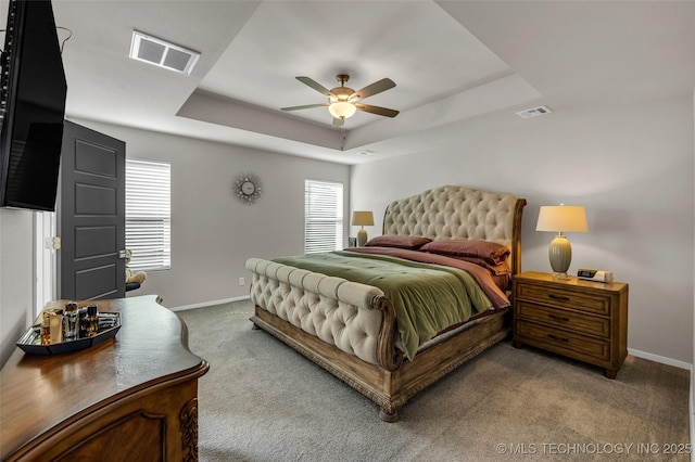 carpeted bedroom with multiple windows, a raised ceiling, and visible vents