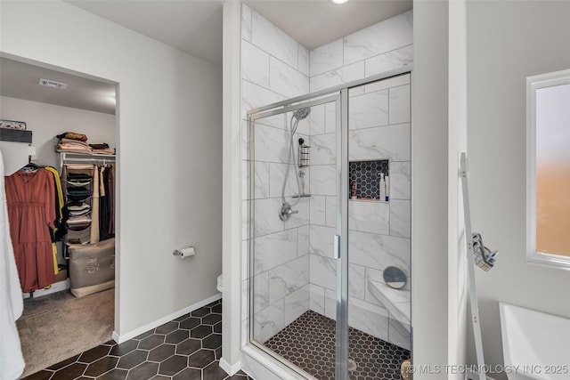 full bath with a shower stall, visible vents, baseboards, and a walk in closet