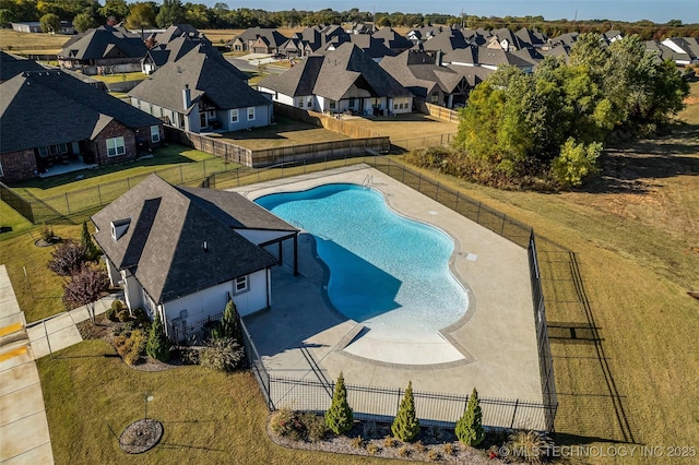 pool with a patio area, a fenced backyard, a residential view, and a lawn