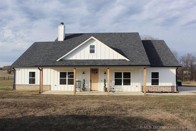 modern farmhouse with a shingled roof, a chimney, a front lawn, board and batten siding, and brick siding