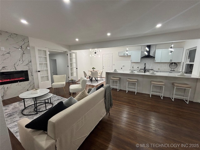 living room with a premium fireplace, french doors, dark wood-style flooring, and recessed lighting