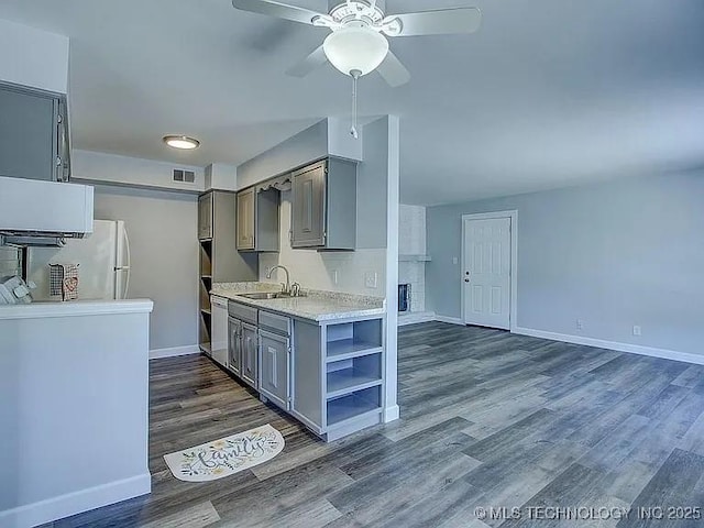 kitchen with light countertops, gray cabinets, white appliances, and a sink