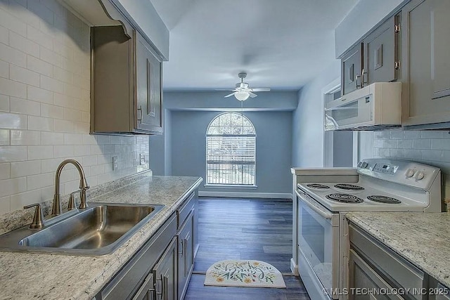 kitchen with dark wood-type flooring, a ceiling fan, a sink, white appliances, and baseboards