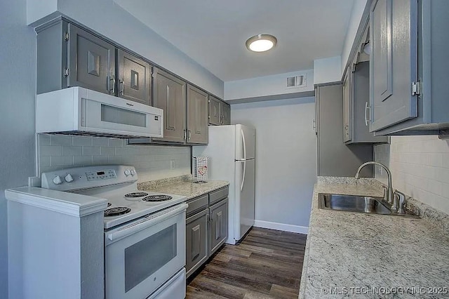 kitchen featuring white appliances, dark wood-type flooring, a sink, visible vents, and light countertops