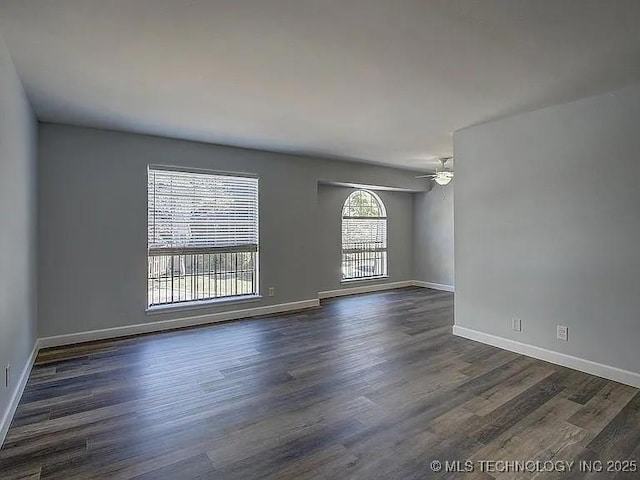 unfurnished room featuring baseboards, dark wood finished floors, and a ceiling fan