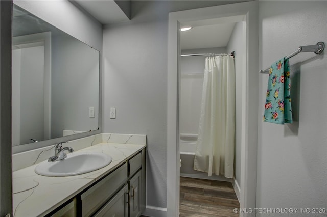 bathroom with baseboards, shower / bath combo with shower curtain, wood finished floors, and vanity