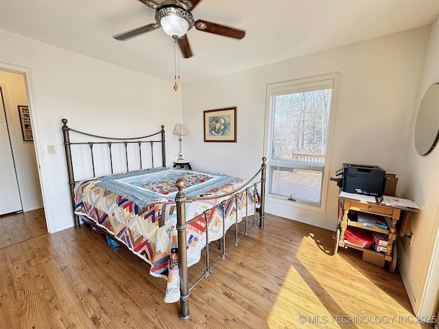 bedroom featuring ceiling fan, baseboards, and wood finished floors