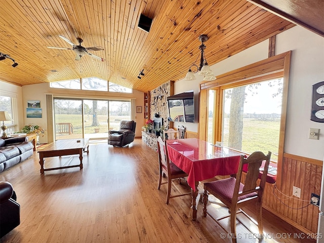 dining space with a wainscoted wall, a ceiling fan, vaulted ceiling, wood finished floors, and wooden ceiling